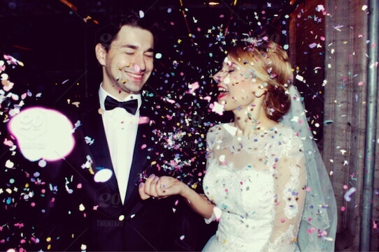 Photo of a bride and groom being showered in confetti while celebrating their wedding