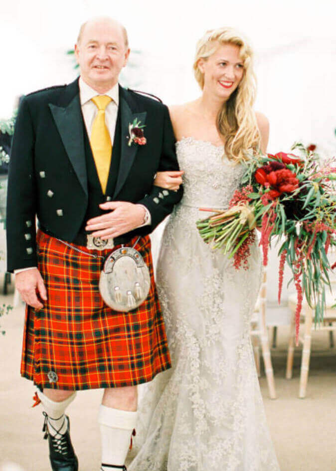 Photo of a father dressed in a kilt walking his bride daughter down the aisle at a wedding