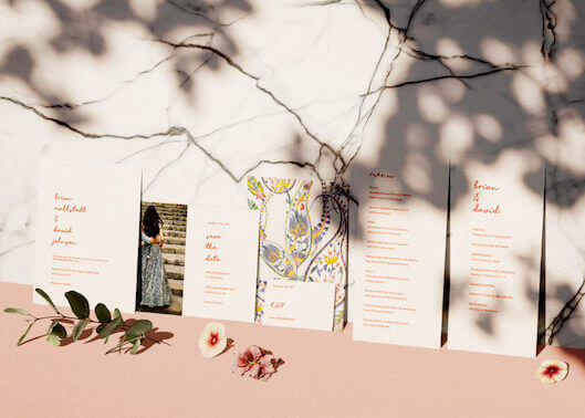 Photo of wedding website invitations leaning tastefully along a marble wall