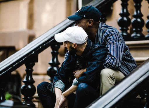 Photo of newly engaged men sitting on a stoop in New York City